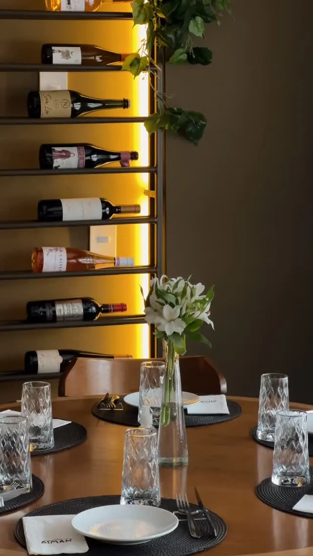 Parede de vinhos iluminada e mesa do salão do Atman