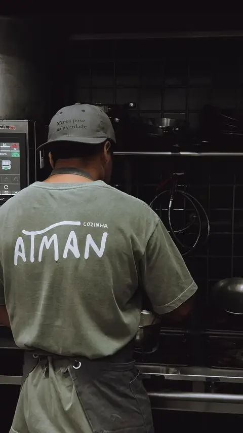 Alan Marcos de costas na cozinha, com a camiseta do Atman